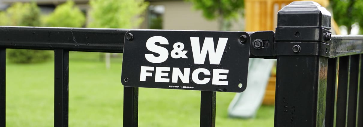 S&W Fence sign shown close up with playground in the backyard