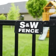 S&W Fence sign shown close up with playground in the backyard