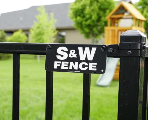 S&W Fence sign shown close up with playground in the backyard